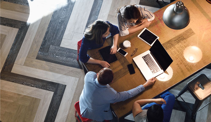 Birds-eye-view of a team gathered with technology (laptop, tablets, phones)